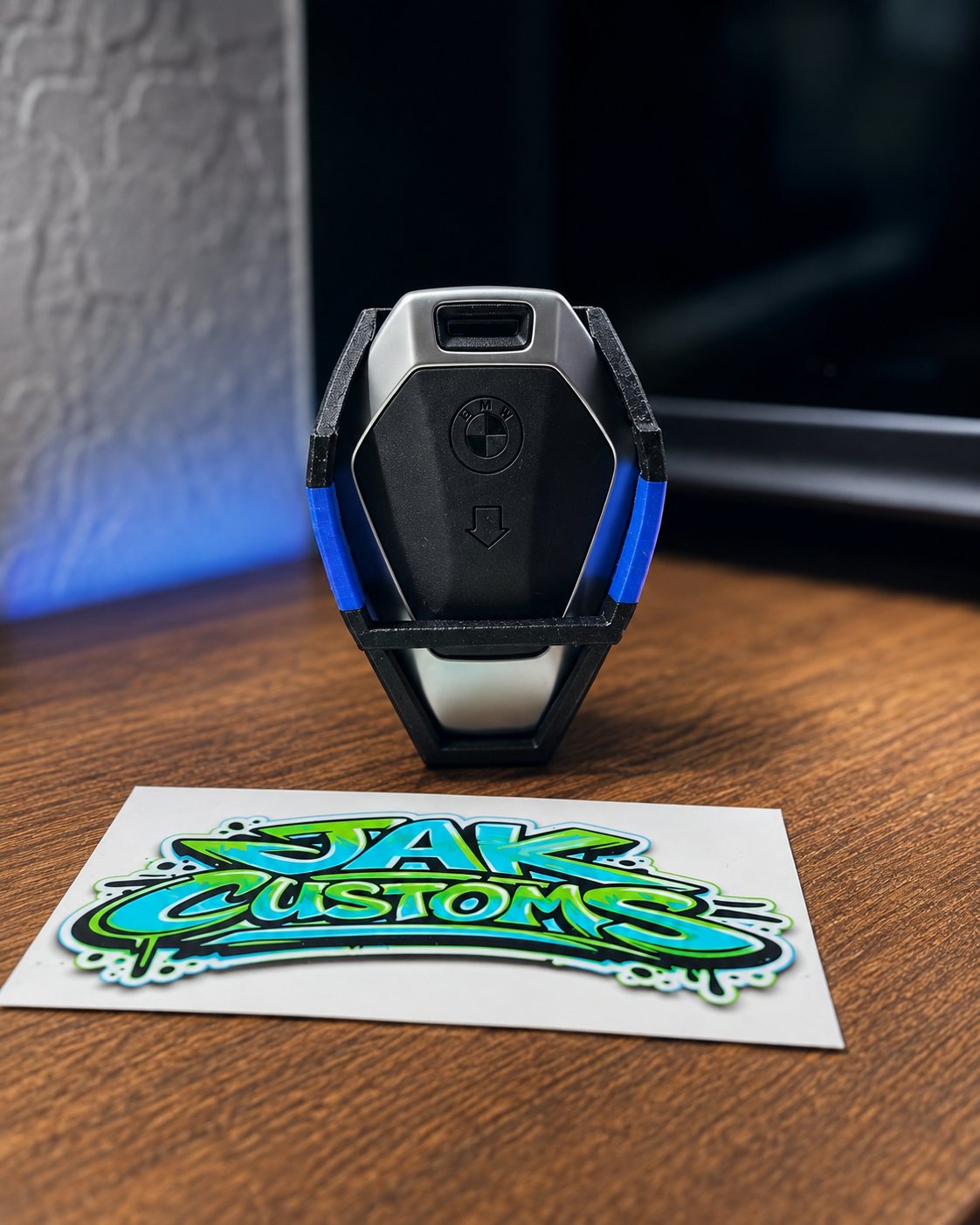 Small black and blue printed accessory beside a JAK Customs sticker