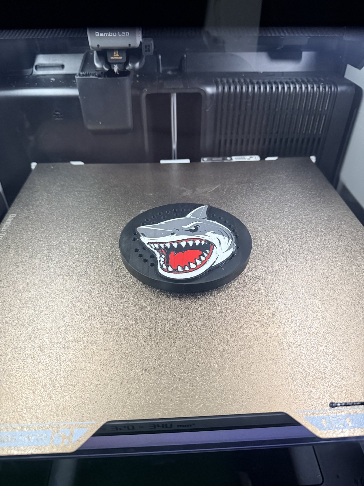 Custom shield-shaped siren cover on a 3D printer bed