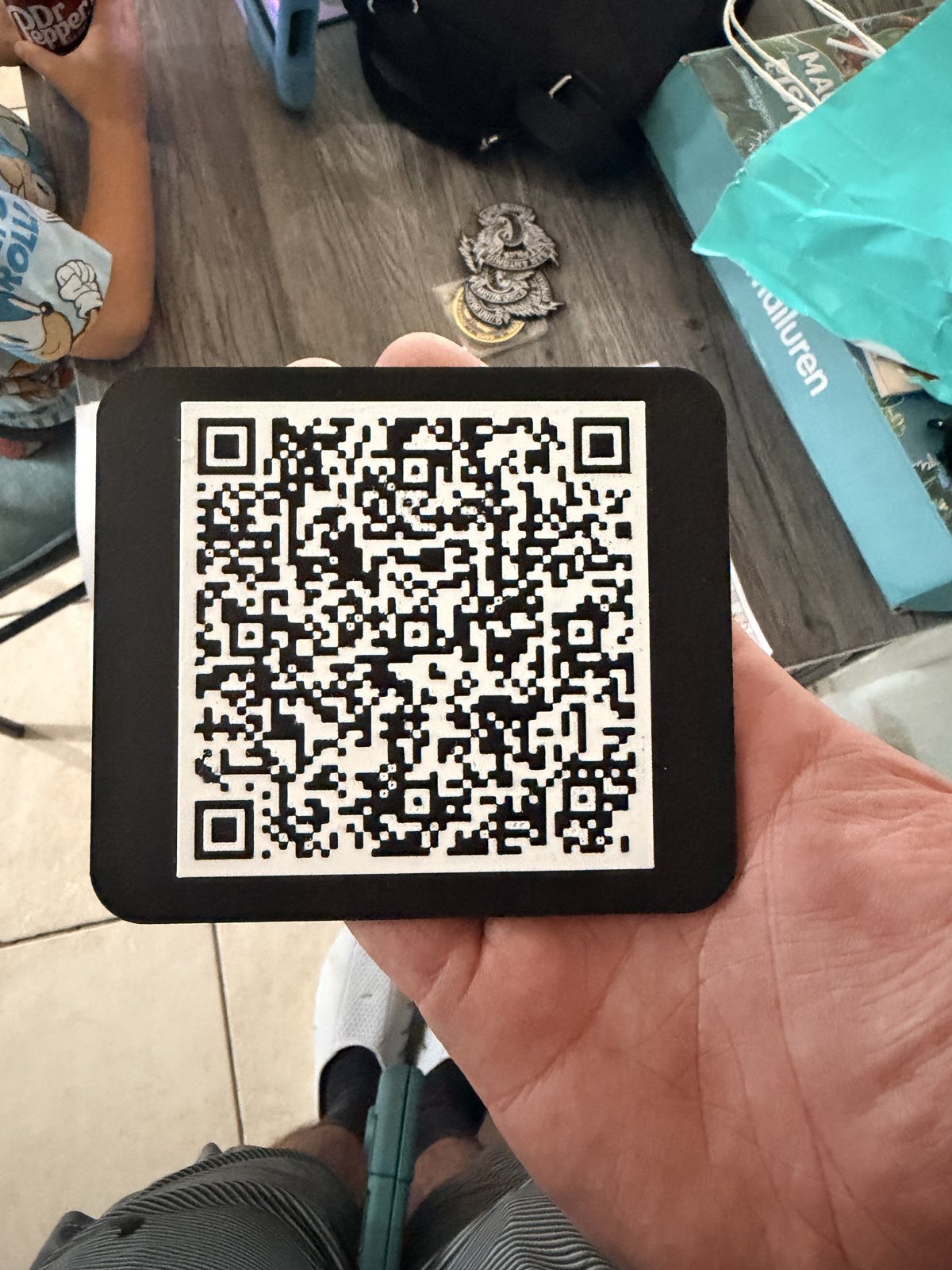 Small printed tag with a QR code held in one hand