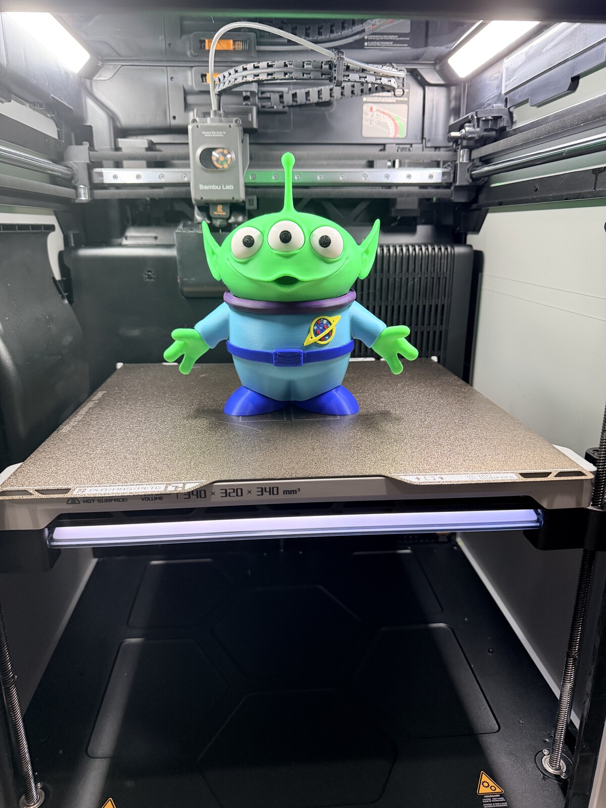 Three-eyed green alien toy figure, printed and painted