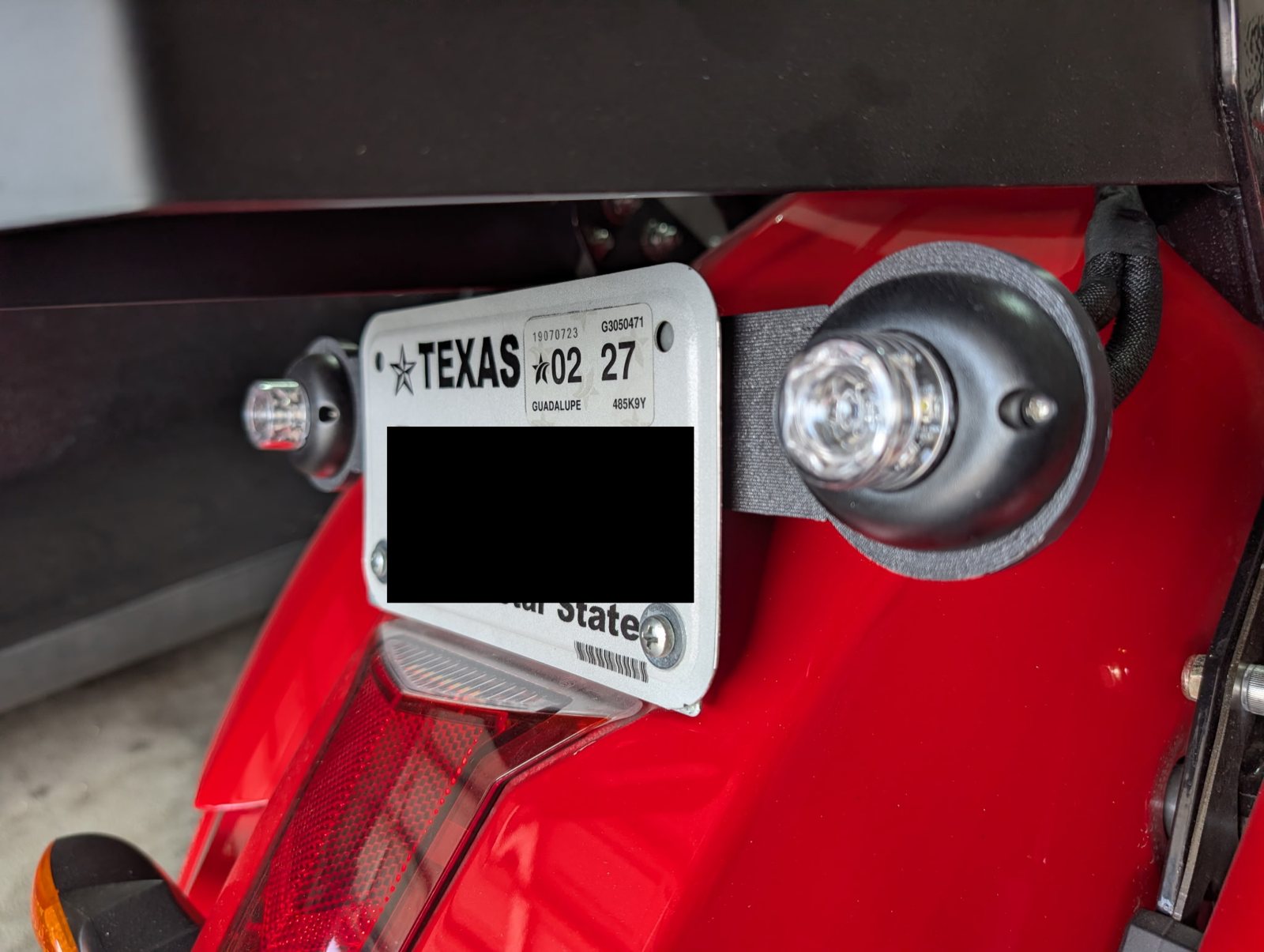 License plate and round light mounted on a red motorcycle