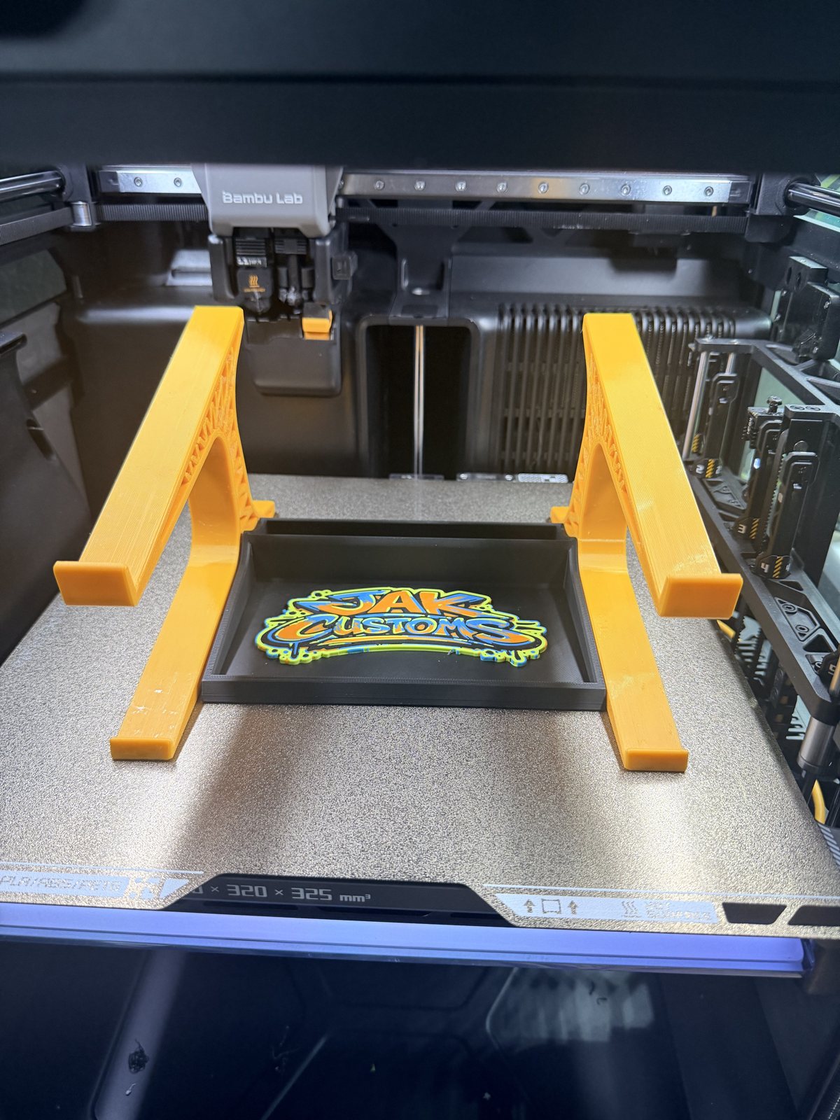 Pair of orange printed support brackets on a printer bed