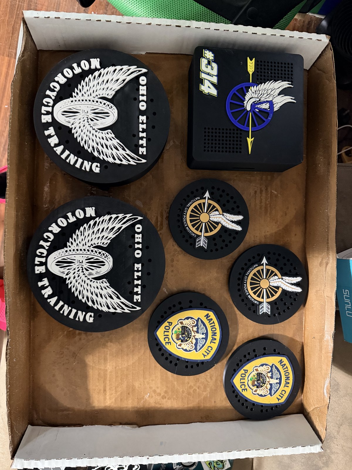Assorted black siren covers with department emblems in a box